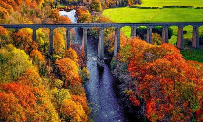 An aerial view of the iconic Pontcysyllte Aqueduct with the river Dee flowing below it and the beautiful countryside.